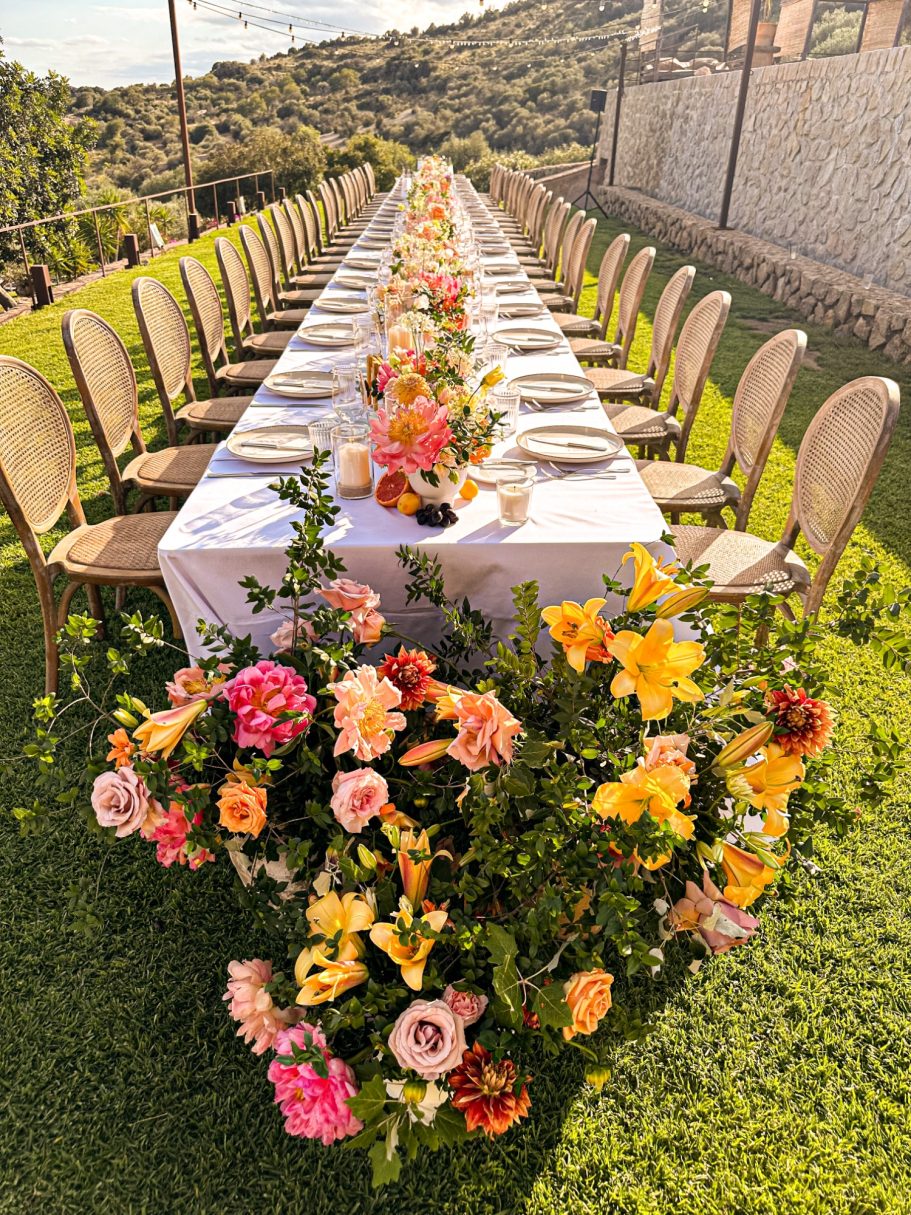 Lange Hochzeitstafel auf einer Finca mit floraler Dekoration, stilvoll eingedeckt für eine Sommerhochzeit auf Mallorca 

