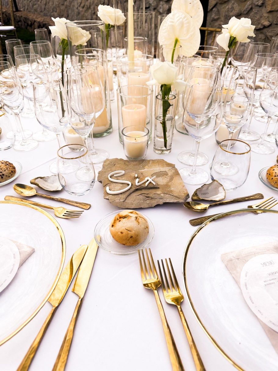 Detailaufnahme eines festlich gedeckten Hochzeitstisches mit goldenen Bestecken, Menükarte und Kerzen

